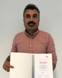 Cemal Yalcin hält sein Zeugnis zum erfolgreichen Abschluss in Betriebslogistik