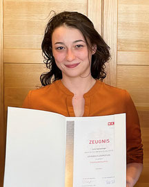 Julia Hamedinger hält stolz ihr Lehrabschlusszeugnis im Einzelhandel