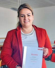 Blerta Agushi hält stolz ihr Lehrabschlusszeugnis im Einzelhandel