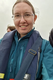 Birgit sitzt am Speedboot mit Schwimmweste und warm angezogen