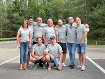 Team von Schreiner Großmann steht gemeinsam auf einem Parkplatz vor Waldkulisse