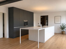 Moderne Küche nach Maß mit weißer Kochinsel, filigranem Tischgestell und anthrazitfarbener Hochschrankzeile, geplant und gefertigt von Holzdesign Rapp