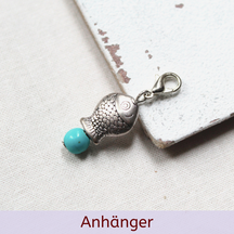 Silberner Fischanhänger mit türkisfarbener Perle als Produktfoto auf Stoff. Text: ‚Anhänger‘.