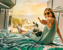 Frau sitzt auf dem Bett im Camper Van mit Französischer Bulldogge 2026
