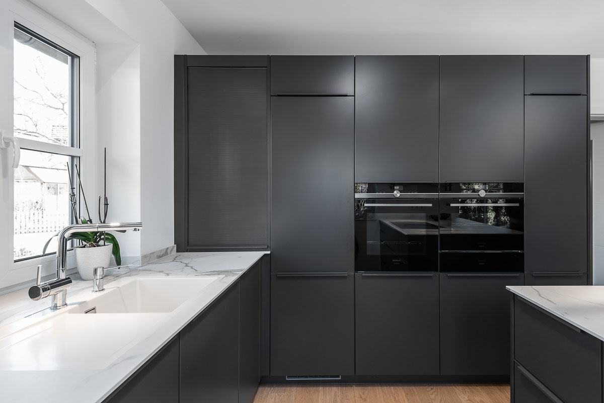 Interieurfotografie: moderne schwarze Küche mit Einbaugeräten und klarer Planung