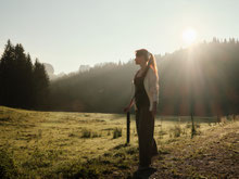 Frau steht bei Sonnenaufgang auf einer Almwiese