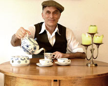 Thommi Baake bei einer Ostfriesischen Teezeremonie zu Hause am runden Tisch mit Friesischem Blau Porzellan, Tee wird eingeschenkt