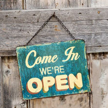 A rustic sign saying come in we're open