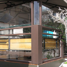 Eck-Lösung eines höhenverstellbaren Windschutzes auf einer Gastro-Terrasse – manuelles Up-and-Down-System für flexiblen Wetterschutz.