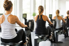 Frauen trainieren auf Rudergeräten in einem Fitnessstudio. Das Ganzkörpertraining unterstützt Muskelaufbau, Muskelkraft, Ausdauer und einen aktiven Stoffwechsel.