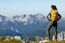 Wanderin in den Bergen als Symbol für körperliche Aktivität, Ausdauer und gesunde Muskulatur.