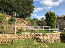 La façade de pierre entourée d'arbres du gite de la gorre à louer en ardeche