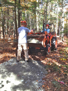 Adrian Curtis, a student with ACCESS, directing Michael Nerrie with a tractor-bucket load of gravel. They are building an accessible hiking trail to one of the vernal pools at Distant Hill Gardens.