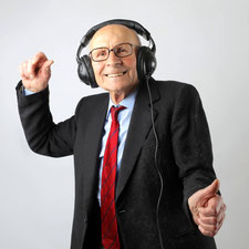 Ein alter Mann tanzt lachend mit Kopfhörern