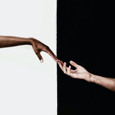 Eine farbige und eine hellhäutige Hand berühren einander