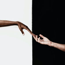 Eine farbige und eine hellhäutige Hand reichen einander