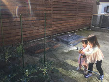 フェンスと水やりする子どもの写真