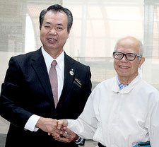 黒島診療所に久保利夫医師(右)が就任。川満町長から委嘱状が手渡された=1日午前、町長室