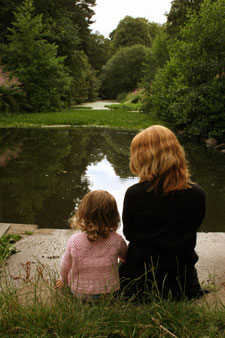 Mutter und Kind sitzen am Teich