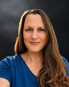 Sandra Mennel sitzend vor einer schwarzen Wand