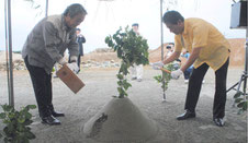安全祈願祭でクワ入れを行う井上局長(右)と外間町長=8日