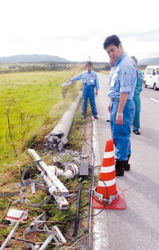 倒壊した電柱を視察する内閣府の松本政務官=30日午後、石垣市宮良
