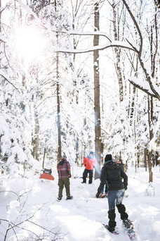 Photo d'une équipe qui fait une randonnée en raquettes en hiver pendant un team-building dans les cantons de l'Est au Québec pour Évasions Canadiana par Marie Deschene photographe pour Pakolla