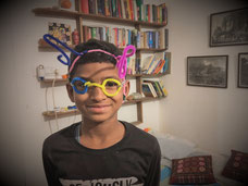 Boy with hand-made pipecleaner glasses (creativity class)