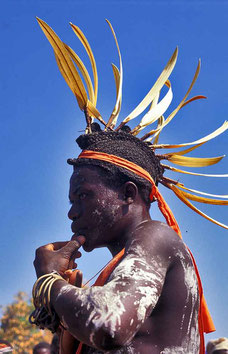 Danseur de gbòrò avec cimier en plumes blanches de calao jouant du sifflet. Son corps est couvert de kaolin. © P. Kersalé 1999-2024.