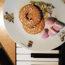 Kekse und Gummibärchen auf einem Teller, das auf Klaviertasten steht