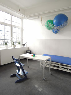 Ergotherapie-Behandlungsraum mit Tisch, Liege und Gymnastikbällen