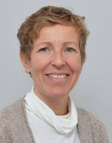 Porträt der lächelnden Christine Harnik vor neutralem, hellem Hintergrund.