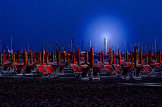 Liegestühle am abendlichen Strand vor Leuchtturm