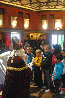 Der kniende Nikolaus übergibt einem kleinen Jungen einen echten Schokonikolaus.