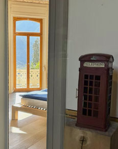 Blick in das Zimmer Townend, Sicht vom Fenster auf Semione, englische Telefonkabine beim Eingang