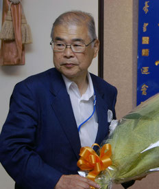 受賞祝いの花束を持つ高橋保一氏