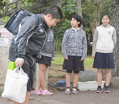 校門前の線で止まってあいさつする児童。写真右は嵩原さん=6日、宮良小学校