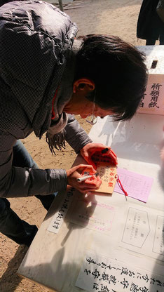 塾長の保本順が、大阪天満宮で絵馬に合格祈願を書いている写真