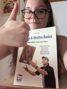 Manu Holmer zeigt Daumen nach oben und hält Cajon-Buch von Peter Lorson