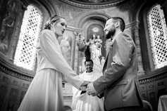 Un couple échange un regard complice en se tenant la main lors de leur cérémonie de mariage à l’église.