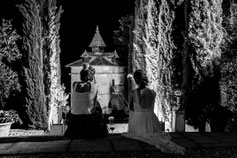 Photographe mariage Tarn-et-Garonne – mariés assis de dos face à un lieu de réception éclairé de nuit en noir et blanc