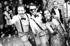 Des invités éclatent de joie en soufflant des bulles de savon, créant une ambiance festive et légère lors d’un mariage.