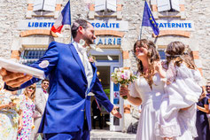 Photo prise par un photographe de mariage à Montauban montrant un couple rayonne de bonheur à la sortie de la mairie après leur mariage civil, entouré de leurs proches sous un ciel ensoleillé.