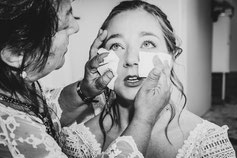 Une mariée, les yeux brillants d'émotion, se fait essuyer les larmes par une femme attentionnée, capturant un instant intense de tendresse et de complicité.