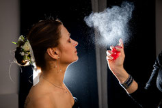 Photo prise par un photographe de mariage à Montauban montrant une mariée reçoit une touche finale de parfum, sublimée par une lumière artistique capturant la magie du moment.