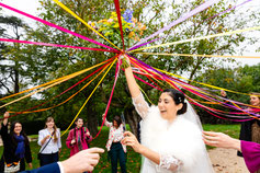 La mariée, radieuse, lève son bouquet entouré de rubans colorés, tandis que ses proches participent avec enthousiasme à cette tradition joyeuse.