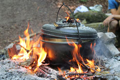 Kochtöpfe brutzeln über dem offenen Feuer – erlebnispädagogische Aktivität in der Natur für Klassenlager und Teamevents