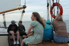 Jugendgruppe sitzt auf Segelschiff - gemeinsam mit anderen Jugendlichen bei dieser Jugendreise eine tolle Zeit erleben
