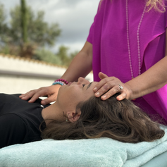 Eine Dame legt ihre Hand sanft und mit viel gefühl auf das Sahasrara Chakra (Kronenchakra) auf den Kopf. Die andere hand liegt auf dem Herzchakra Anahata. Sie bekommt eine Cranio-behandlung. Traumalösung durch Energiearbeit udn bewusstseinsarbeit. 
