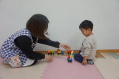 車のおもちゃで遊ぶ子供と保育士